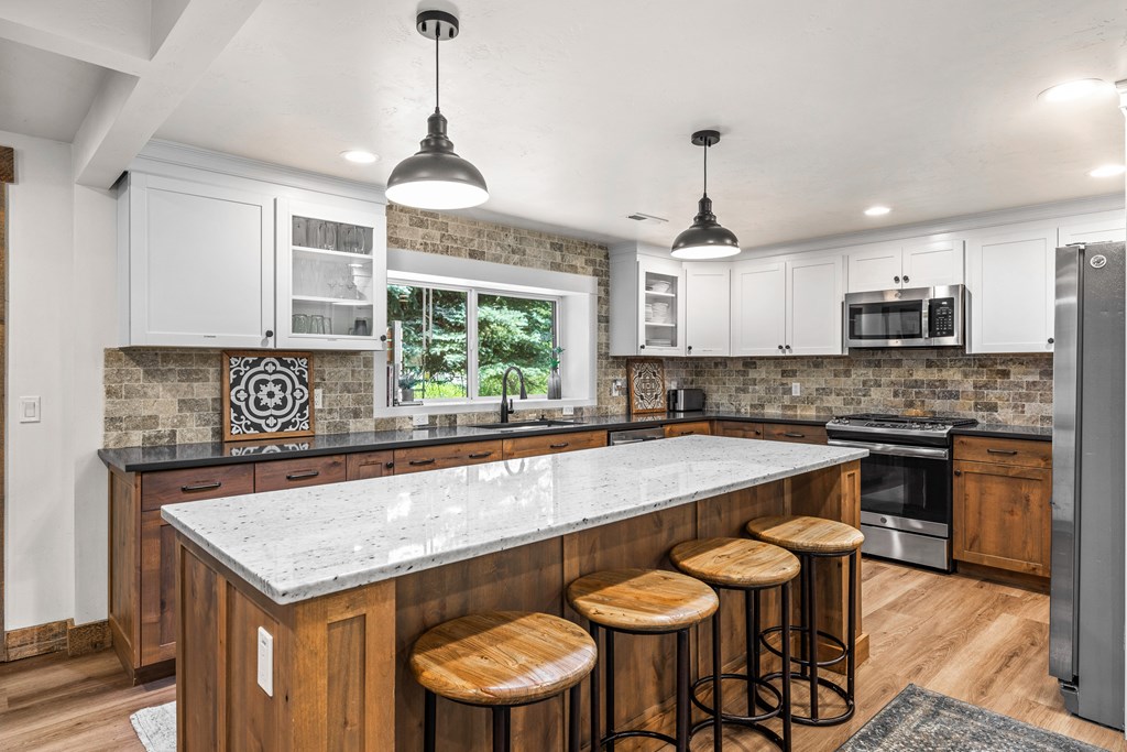 Fully renovated kitchen with large quartz island, stainless appliances, and wood cabinetry — a stylish and functional centerpiece for family gatherings or guests.