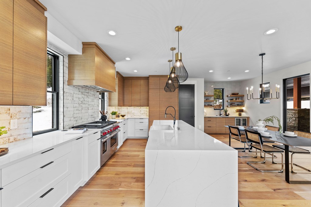 Chef’s kitchen with quartz waterfall island, wood cabinetry, and designer lighting. Open-concept layout connects seamlessly to the dining area for entertaining.