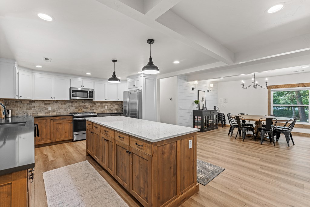 Spacious kitchen and dining area with wood floors, modern lighting, and shiplap details — ideal for vacation rental hosting or everyday living.