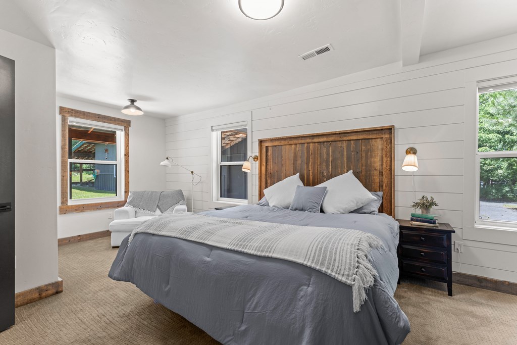 Main-level primary suite with rustic wood headboard, shiplap walls, and natural light — a cozy retreat in this McCall mountain home.
