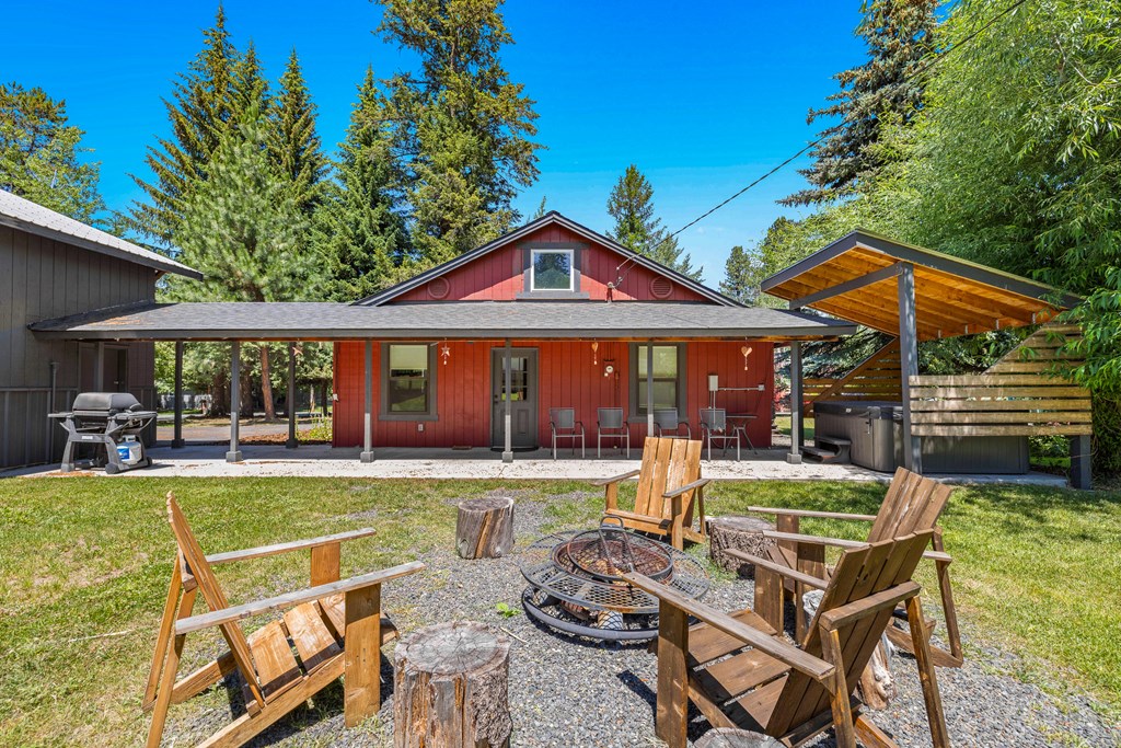 Private backyard with covered patio, firepit lounge, and hot tub area — built for relaxing after a day on the lake or mountain.