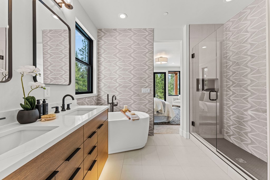 Luxury en suite bath with soaking tub, double vanity, geometric accent wall, and glass shower — a perfect spa-style retreat.