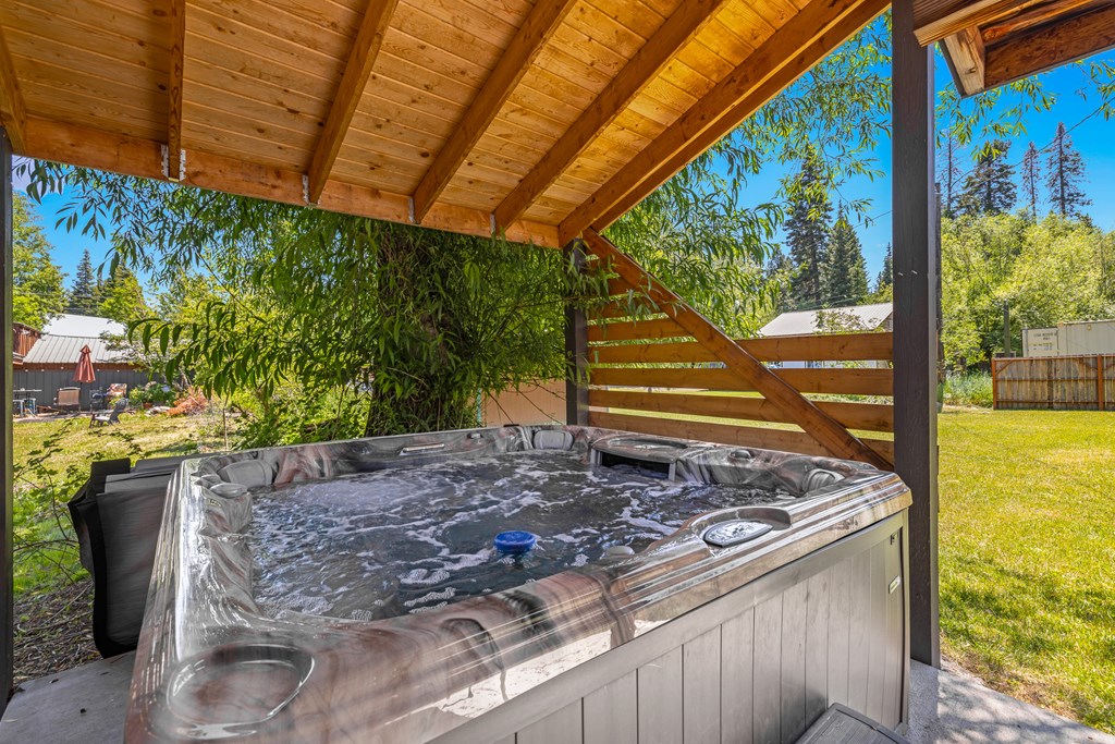 Outdoor hot tub under a wood pergola surrounded by trees — the ultimate mountain getaway amenity for year-round enjoyment.
