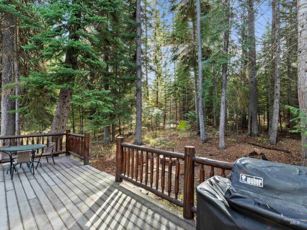 ack deck and wooded fire pit area at 1034 Fireweed Drive in McCall, Idaho — Trex deck surrounded by pine trees with cozy outdoor seating for summer gatherings.