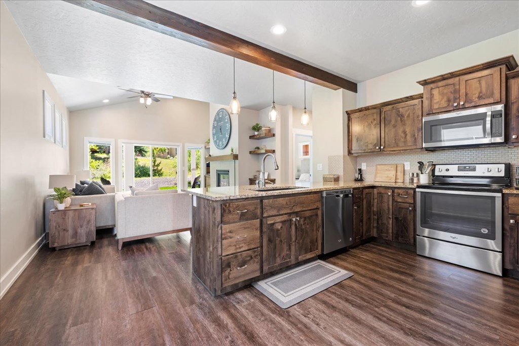Open-concept kitchen in a McCall, Idaho home featuring rustic wood cabinets, granite countertops, stainless steel appliances, and pendant lighting. This McCall real estate listing blends mountain style with modern finishes for a warm, inviting space.