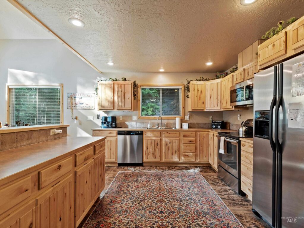 Kitchen inside 1034 Fireweed Drive cabin in McCall, Idaho featuring stainless steel appliances, warm wood cabinets, and mountain cabin design.
