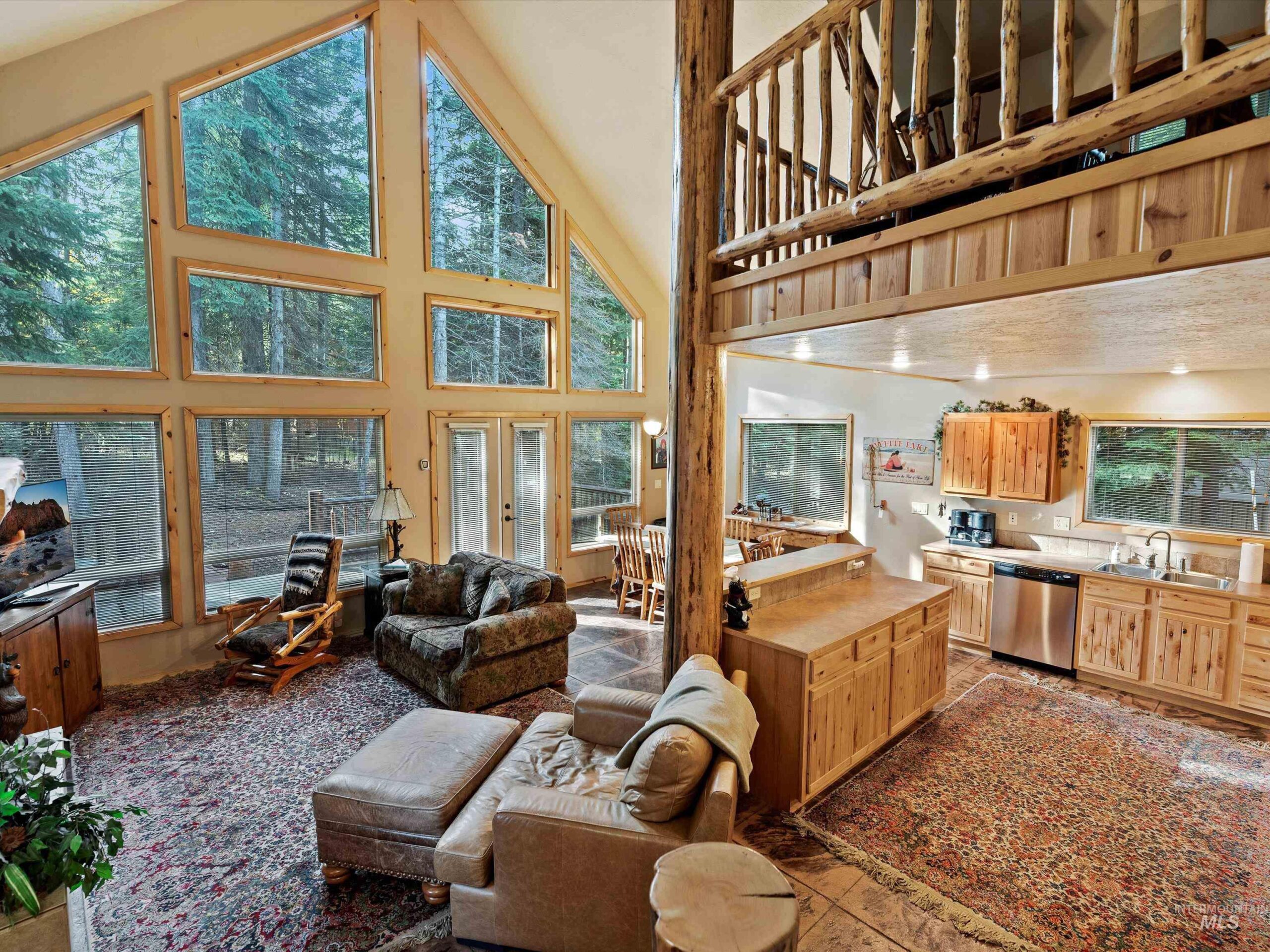 Front exterior of 1034 Fireweed Drive in McCall, Idaho — a classic mountain cabin surrounded by pine trees with a Trex deck and natural wood finishes.