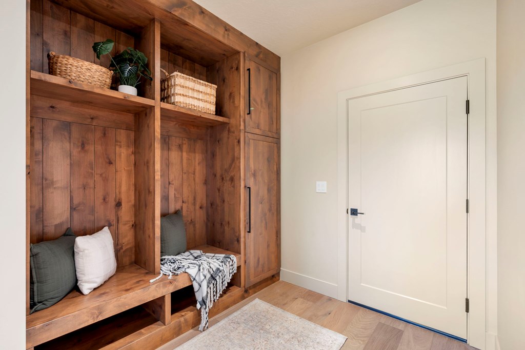 Built-in wood mudroom lockers with bench seating, storage cubbies, and hooks near the garage entry of a McCall Idaho mountain home.