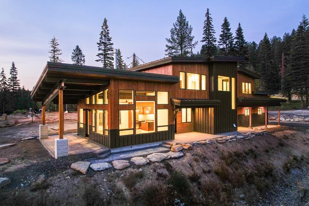 Modern ski-in, ski-out mountain home near Brundage Mountain Resort with warm interior lighting and forest backdrop at dusk.