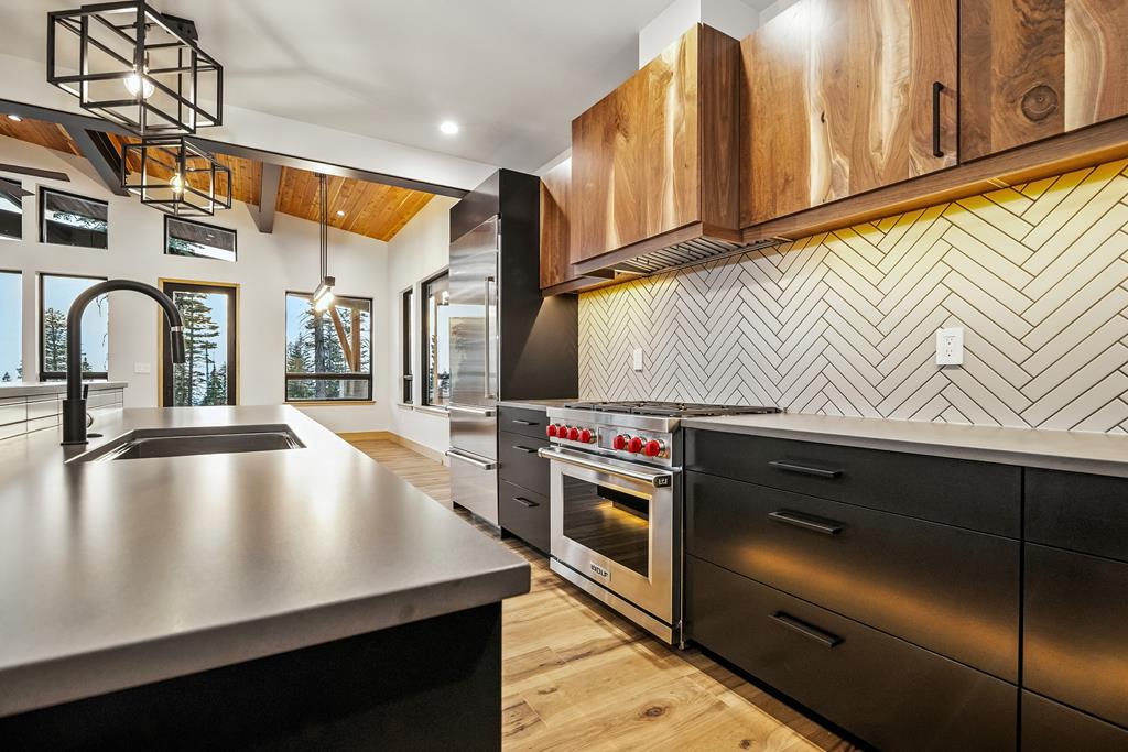 Luxury kitchen with quartz countertops, herringbone tile backsplash, walnut cabinets, and high-end stainless steel range.