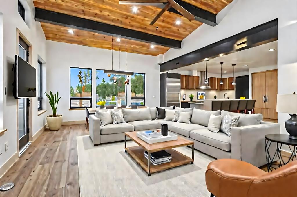 Staged mountain living room with large sectional sofa, open kitchen, and modern wood ceiling with recessed lighting.