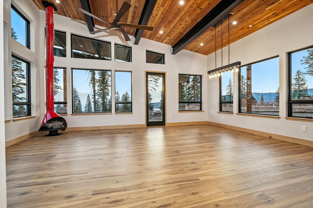 Vaulted great room featuring red suspended fireplace, panoramic windows, and views toward Brundage Mountain ski terrain.