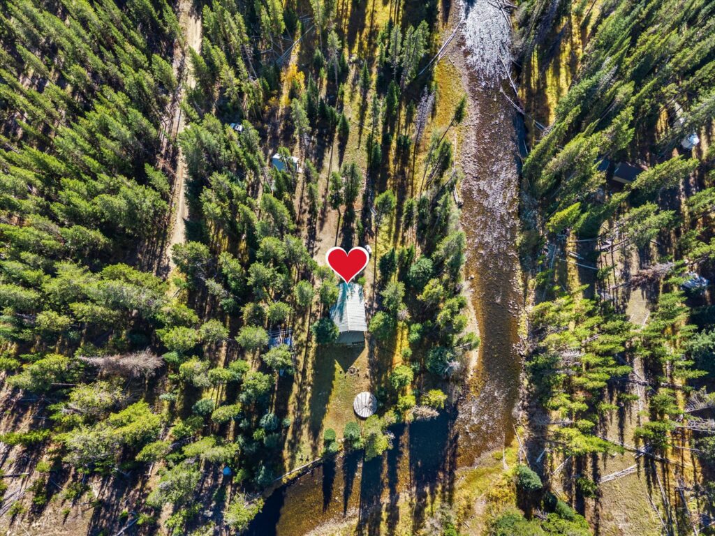 Overhead drone view of the log cabin at 507 Secesh River Road, marked with a heart, with the Secesh River alongside