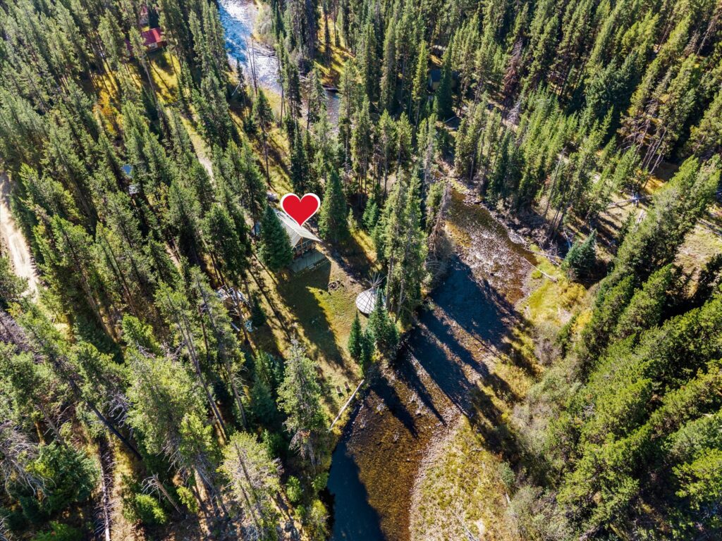 Aerial view of the cabin, fire ring and teepee platform, with the Secesh River bending around the property