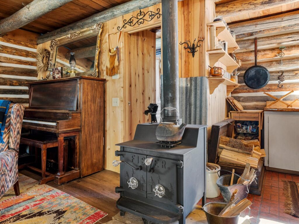 Black wood stove and an old upright piano tucked into a corner of the cabin