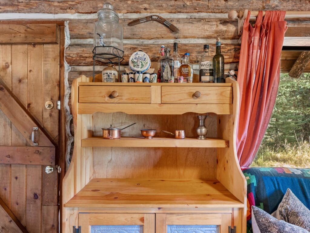 Pine hutch beside a plank door, set against hand-hewn log walls