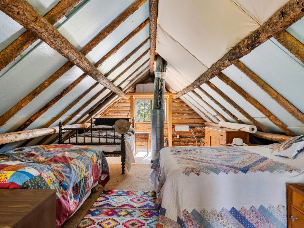 Loft bedroom under the gable with two beds and colorful quilts