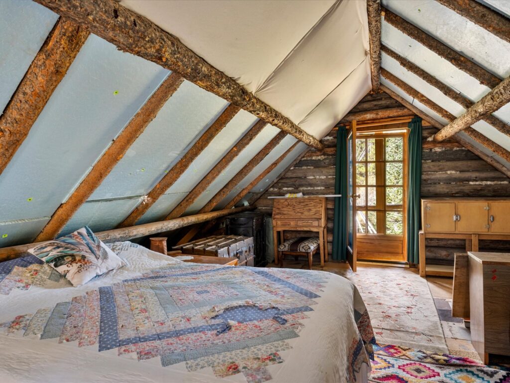 Loft bedroom with a quilted bed and a door opening to the upper balcony