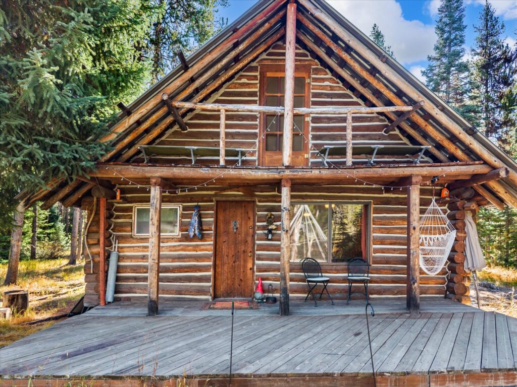 Covered front porch of the log cabin with room for chairs and a hammock
