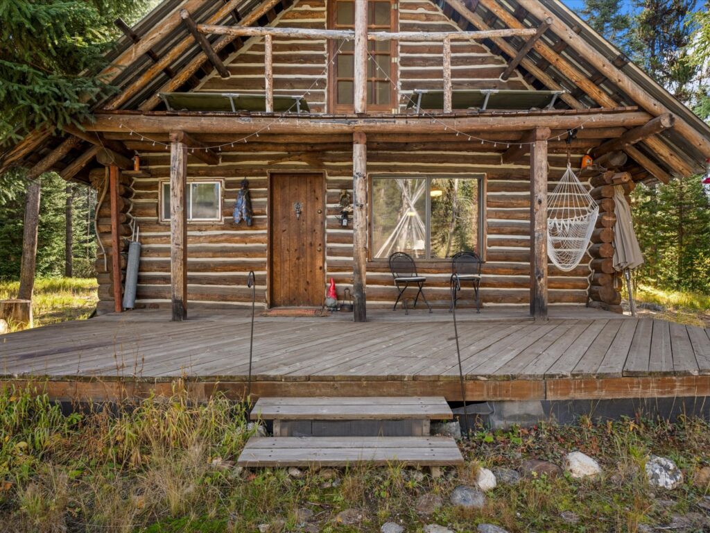 Front of the log cabin and covered porch seen from the yard